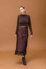 Falda midi de seda con estampado de lunares rojos sobre fondo oscuro, con detalle de encaje negro en el ruedo.