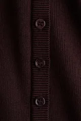 Remera de punto fino ajustada al cuerpo, con mangas largas, escote cuadrado pronunciado y tapeta frontal con botones decorativos.