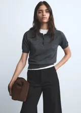 Jeans wide leg tiro alto de color negro, con cierre delantero de cremallera y botón, trabillas para cinturón y dos bolsillos de parche en la parte delantera.