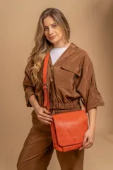 Bandolera de diseño simple con tapa frontal, correa ajustable y división interna con bolsillos. Fabricada en material símil cuero.