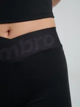 Biker deportiva Umbro para mujer, de color negro, confeccionada con tejido elástico y pretina cruzada con elástico personalizado de la marca.