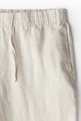 Pantalón de lino liviano para hombre, de corte regular fit y color beige. Presenta cintura elástica con cordón de ajuste oculto, bolsillos laterales discretos y un bolsillo trasero insertado.