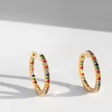Par de aros tipo argolla dorados con cristales multicolores en el frente y en el interior. Cierre a bisagra.