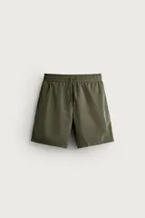 Short de baño largo en color beige, confeccionado en tejido técnico con tacto aterciopelado. Cuenta con cintura elástica ajustable con cordón, bolsillos laterales y detalle de bolsillo trasero, además de forro interior.