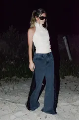 Jeans de corte wide leg en denim negro lavado, con inserción lateral de encaje negro adornado con flecos y lentejuelas.