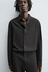 Camisa de corte relajado, color azul marino, con cuello solapa, manga larga con puños abotonados y cierre frontal de botones.