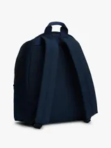 Mochila de diseño redondeado color azul marino, con asa superior, correas ajustables y acolchadas. Presenta un compartimento principal con cierre, bolsillo exterior con cremallera y parche con el logo de Tommy Jeans en la parte delantera.