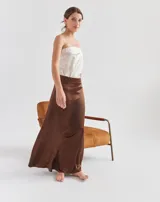 Top strapless de color beige, con diseño liso y ajuste al cuerpo. Cuenta con forro interno con elástico en el busto para mayor sujeción y pequeños tajos laterales en el ruedo.
