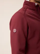 Campera softshell color gris, con cierre frontal completo, cuello alto y bolsillos laterales y en el pecho con cierre. Cuenta con logo bordado en el pecho y ajuste en los puños.