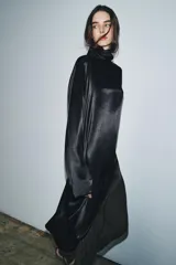 Blusa de Zara Woman Collection confeccionada en viscosa, con cuello alto, manga larga y diseño asimétrico en el bajo. Presenta un acabado satinado y cierre en la espalda.