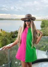 Vestido corto de diseño bicolor con paneles verticales en colores fucsia y verde. Presenta un corte recto y holgado, sin mangas, con cuello redondo.