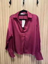 Blusa azul petróleo de seda con cuello clásico y corte asimétrico, más larga en la parte trasera.