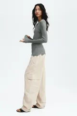 Pantalón cargo de nylon de corte oversized con leve efecto arrugado, cintura elástica fruncida, bolsillos con cierre en el frente y bolsillos con solapa en las piernas.
