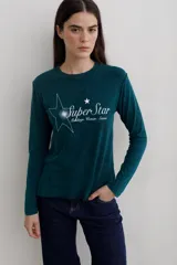 Remera de manga larga con efecto lavado, cuello redondo y estampa frontal con diseño de estrella y texto.
