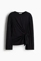 Top negro de manga larga con escote redondo y un nudo ajustable en el lateral inferior.