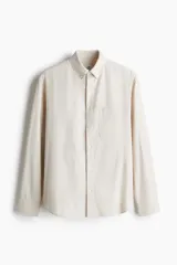 Camisa color crema de corte regular, con cuello abotonado, manga larga y bolsillo en el pecho.