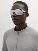 Lentes de sol deportivos tipo máscara con armazón plateado y cristales espejados plateados, de diseño envolvente y moderno.