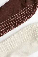 Pack de dos pares de medias de yoga antideslizantes de punto fino con caña acanalada, una en color blanco y otra en color marrón, con puntos de agarre en la suela.