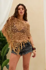 Top corto tejido en crochet de color beige con diseño de red, adornado con lentejuelas circulares y flecos en el borde inferior.