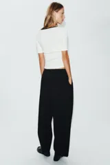 Camiseta blanca de manga corta y corte slim fit, con escote redondo ribeteado en negro, detalle de frunce en el centro del pecho y un pequeño lazo negro decorativo.