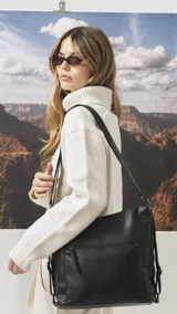 Cartera mochila de diseño versátil en color negro, confeccionada en símil cuero con textura granulada. Cuenta con un bolsillo frontal con cierre, correas ajustables y herrajes metálicos. Su diseño permite llevarla tanto al hombro como en la espalda.