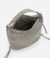 Bolso grande tipo hobo desestructurado, color gris claro con acabado ligeramente brillante o envejecido. Cuenta con dos asas cortas y una correa larga desmontable. Presenta detalles de cierres o tiradores decorativos en los laterales y cierre principal superior con cremallera.