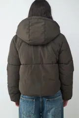 Campera puffer de corte recto y diseño acolchado, con capucha fija, manga larga y cierre frontal con cremallera.
