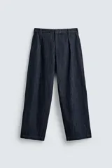 Pantalón de corte barrel fit confeccionado en denim de algodón rígido color azul oscuro. Presenta cintura con pliegues frontales, bolsillos laterales y bolsillos traseros de vivo. Cierre frontal con cremallera y gancho metálico oculto.