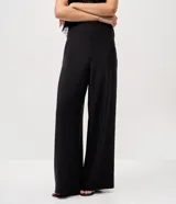 Pantalón de sastrería modelo pantalona, de corte amplio y tiro alto, con cintura lisa y pliegues frontales. Confeccionado en tejido de poliéster con elastano.