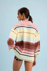 Buzo de algodón tejido, de calce relajado y silueta amplia con diseño de rayas horizontales en tonos pastel de amarillo, celeste, rosa y marrón. Tiene cuello tipo polo con terminación artesanal en crochet y mangas amplias.