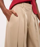 Pantalón de sastre tipo balloon color beige, con pinzas delanteras que aportan volumen, piernas amplias y bajo ajustado. Cuenta con cintura estructurada y pasacintos.