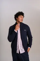 Cardigan de punto color azul marino, con cuello alto, cierre frontal completo y puños acanalados. Presenta el logo de la marca bordado en el pecho.