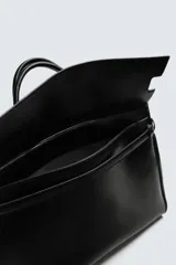 Bolso de mano de gran tamaño en color negro, con diseño estructurado, doble asa superior y cierre magnético. Incluye detalles de cintas laterales y compartimentos internos con cierre.