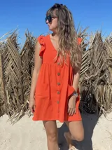 Vestido corto color verde lima, con escote en V, cierre frontal con botones, mangas cortas con volados y bolsillos laterales.