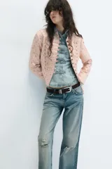 Blazer entallada de cuello alto y manga larga, en color rosado con estampado de flores amarillas. Cuenta con detalle de pasamanería en el delantero y cierre frontal con botones metálicos dorados.