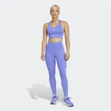 Calza de running ajustada de tiro alto, color lila/lavanda, con tecnología AEROREADY y tejido Adiflex. Presenta bolsillos laterales y detalles reflectantes, incluyendo el logo de Adidas en la parte inferior de la pierna.