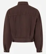 Campera marrón de sarga de algodón, corte regular, cuello inglés, manga larga, abotonada al frente, con bolsillos con solapa en el pecho y pliegues en la parte baja.