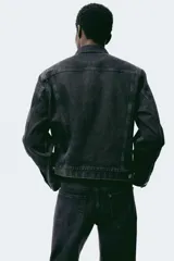 Jean de cinco bolsillos en denim de algodón rígido, color negro con efecto deslavado. Modelo con pierna recta y corte estándar de cintura a bajo, con cierre de botones.