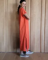 Vestido largo color crema, de corte recto y holgado, con cuello redondo y mangas cortas. Presenta aberturas laterales en la falda.