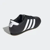 Championes Adidas de cuero negro con las tres tiras blancas y suela marrón.