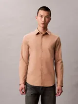 Camisa de manga larga Calvin Klein con corte slim, cuello de punta clásico, cierre frontal con botones a tono y monograma bordado sutilmente en el pecho.