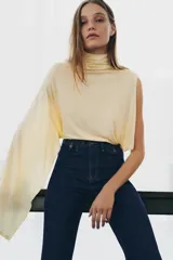 Jeans de tiro alto con corte flare y ajuste slim. Presenta trabillas en la cintura, bolsillos delanteros con detalle de botones metálicos y raya planchada a lo largo de las piernas. Cierre frontal con cremallera y botón.