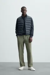 Chaleco acolchado verde oscuro, con cuello alto, cierre frontal con cremallera y bolsillos laterales. Confeccionado en tejido técnico repelente al agua.