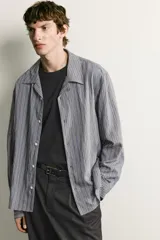 Camisa de corte regular fit confeccionada en tejido fluido con viscosa. Presenta cuello bowling, manga larga con puños abotonados y cierre frontal con botones.