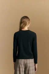 Remera de manga larga en color negro, con cuello redondo y costura vertical central en el frente. Presenta un diseño minimalista de calce ajustado y líneas limpias.