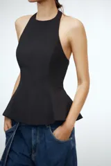 Top rosa claro, entallado, con cuello halter que se abrocha en la nuca y espalda descubierta. El bajo tiene un corte peplum acampanado.
