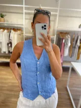 Chaleco de lino 100% color celeste, con escote en V y cierre frontal de botones.