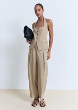 Pantalón de tiro medio color beige con diseño balloon y pinzas en la parte delantera. Cuenta con bolsillos laterales y cierre oculto.
