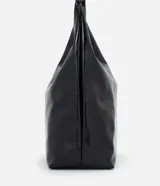 Cartera estilo hobo de gran tamaño, color negro, con superficie texturizada de líneas verticales. Presenta un diseño de media luna con asa ancha fija y abertura superior amplia.