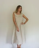Vestido midi de lino color beige, de corte suelto, sin mangas y con escote redondo decorado con un volado amplio.